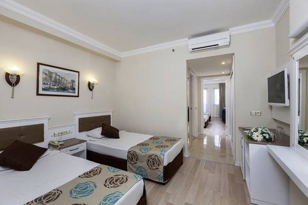 Hotelzimmer von Primasol Hane Family Resort mit zwei Betten, Dekor und Fernseher.