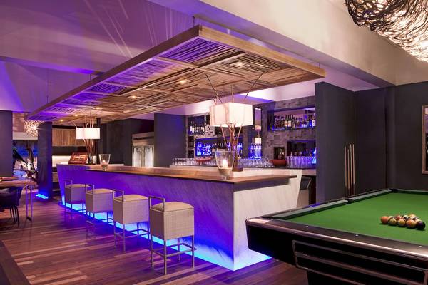 Hotelbar des Taj Coral Reef Resort & Spa mit Bartheke, Sitzgelegenheiten, Pooltisch und Beleuchtung