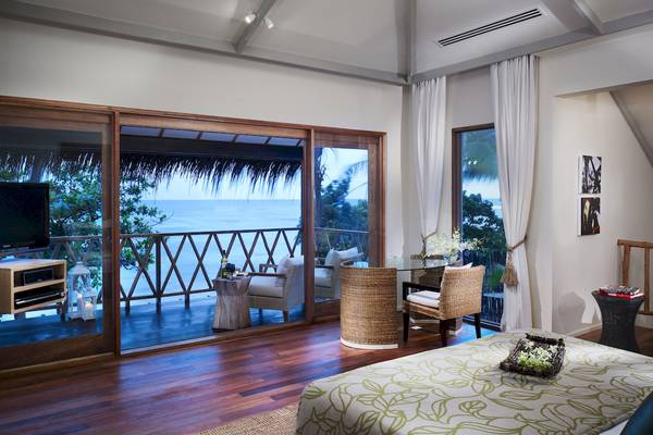Schlafzimmer im Taj Coral Reef Resort & Spa mit Meerblick, Balkon, Fernseher und Möbeln.