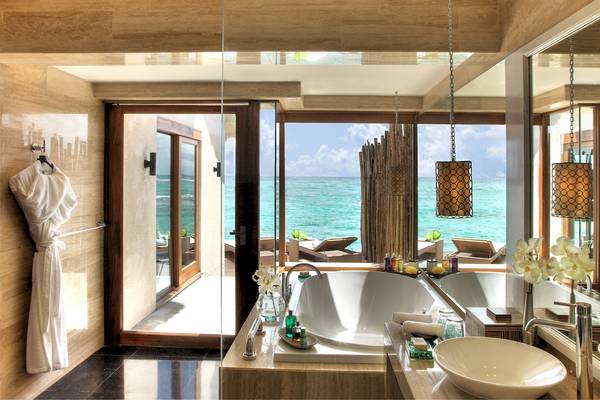 Badezimmer mit Meerblick im Taj Coral Reef Resort & Spa mit Badewanne, Dusche, Toilettenartikeln und Blick auf das Meer.