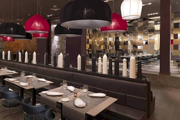 Inneneinrichtung des Restaurants im Paradisus Playa del Carmen mit Tisch und Stühlen, roten und schwarzen Hängelampen.
