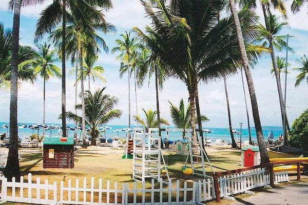 Strand des Cape Panwa Hotels mit Palmen, Sonnenschirmen und Strandspielzeug.