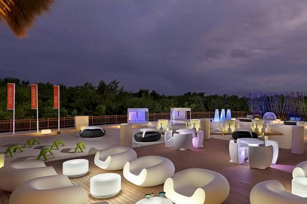 Dachterrasse des Paradisus Playa del Carmen Hotels bei Nacht mit weißen Möbeln und blauer Beleuchtung.
