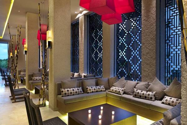 Loungebereich im Paradisus Playa del Carmen Hotel mit Sofas, Kerzen und modernen Kunstwerken.