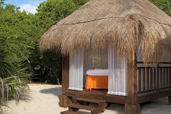 Strandhütte im Paradisus Playa del Carmen Hotel mit weißem Vorhang und oranger Bettdecke