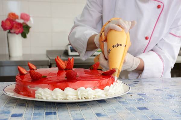 Koch dekoriert Kuchen mit Erdbeeren und Sahne im Paradise Hotel Corfu