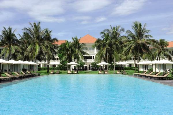 Außenpool des Boutique Hoi An Resorts mit Palmen und Sonnenliegen
