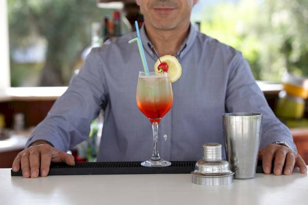 Mann bereitet Cocktail am Tresen des Paradise Hotel Corfu vor