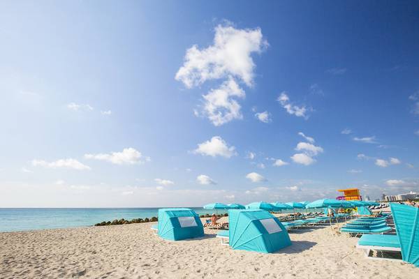 Strand mit blauen Umkleidekabinen und Umbrellas unter einem blauen Himmel