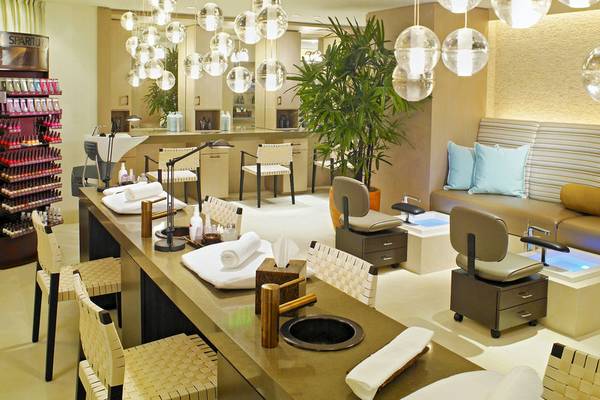Inneneinrichtung des The Palms Hotel & Spa mit langen Tischen, Stühlen, Pflanzen und Leuchten.