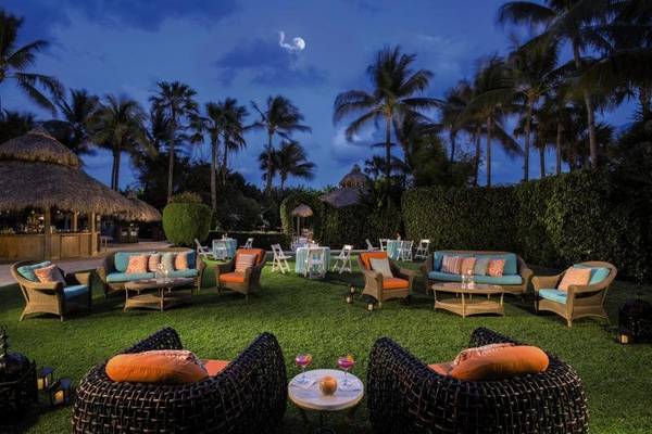 Außenlounge des Palms Hotel & Spa bei Nacht mit tropischen Palmen und farbenfrohen Möbeln.