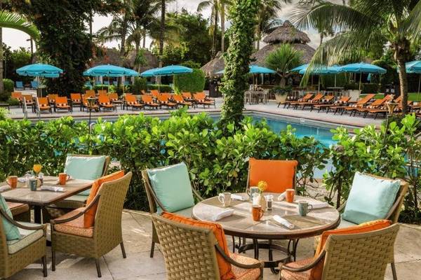 Terrasse des Palms Hotel & Spa mit Tischen, Stühlen und einem Swimmingpool.