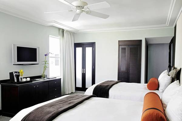 Zwei Betten im Hotelzimmer des Palms Hotel & Spa mit Deckenventilator und Fernseher.
