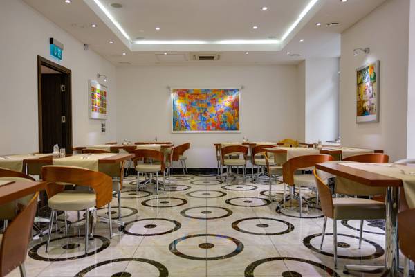 Speisesaal des Best Western Plus Hotels mit runden Mustern auf dem Boden und bunten Gemälden an den Wänden.