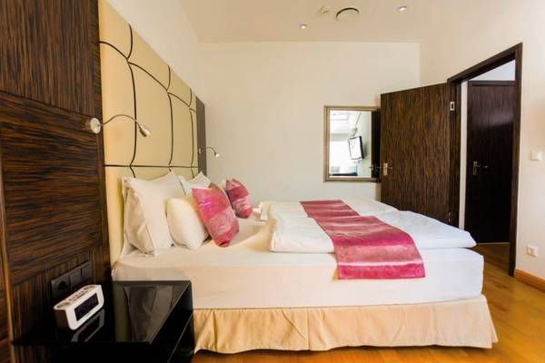 Schlafzimmer im Best Western Plus Hotel mit zwei Betten, rosa Decken, weißen Kissen und einem Fernseher im Spiegel.