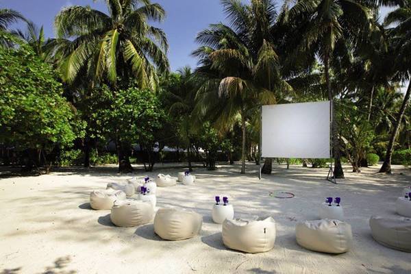 Strandkino im Holiday Inn Resort Kandooma Maldives mit Loungesofas und Palmen