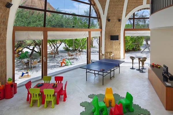 Kinderspielzimmer im Holiday Inn Resort Kandooma Maldives mit Tischtennistisch und bunten Stühlen.