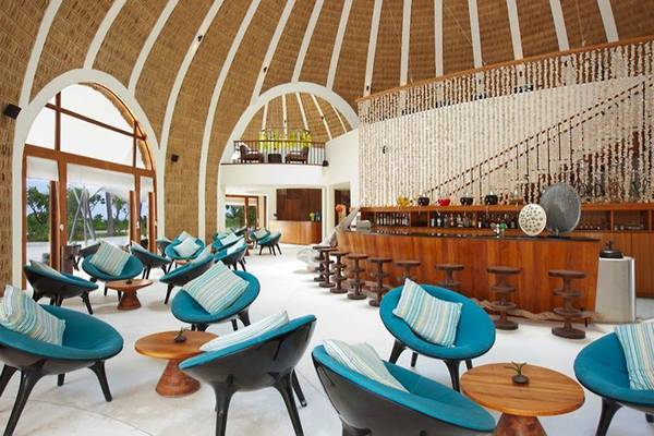 Loungebereich im Holiday Inn Resort Kandooma Maldives mit blauen Stühlen und einem hölzernen Tresen.