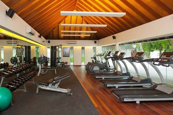 Fitnessstudio im Holiday Inn Resort Kandooma Maldives mit Laufbändern, Hanteln und einer grünen Kugel.