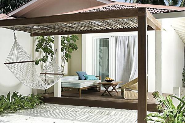 Außenbereich des Holiday Inn Resort Kandooma Maldives mit Hängematte und Terrassenmöbeln.