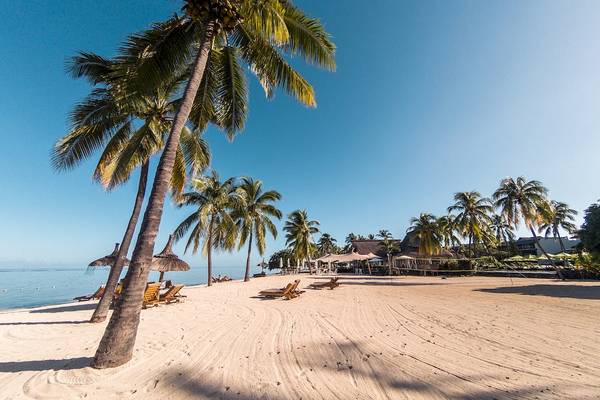 Strand des Sofitel Mauritius L'Imperial Resort & Spa mit Palmen und Sonnenliegen