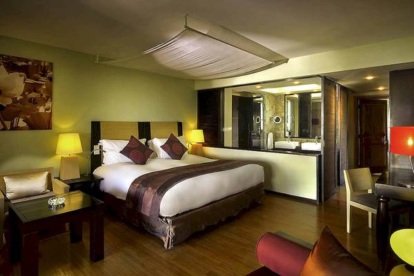 Schlafzimmer im Sofitel Mauritius L'Imperial Resort & Spa mit Doppelbett, Lampen und Dekor.