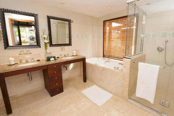 Badezimmer im Sofitel Mauritius L'Imperial Resort & Spa mit Doppelwaschbecken, Badewanne und Glasdusche.