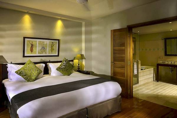 Schlafzimmer im Sofitel Mauritius L'Imperial Resort & Spa mit Bett, Kissen, Lampe und Badezimmer mit Badewanne