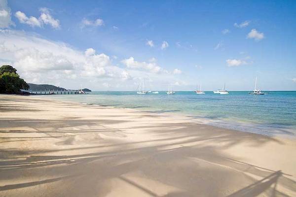 Strand am Cape Panwa Hotel mit weißen Segelbooten im Ozean