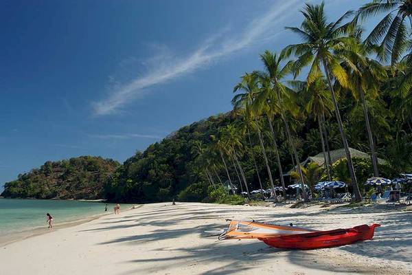 Strand des Cape Panwa Hotels mit roten Kanus und Palmen