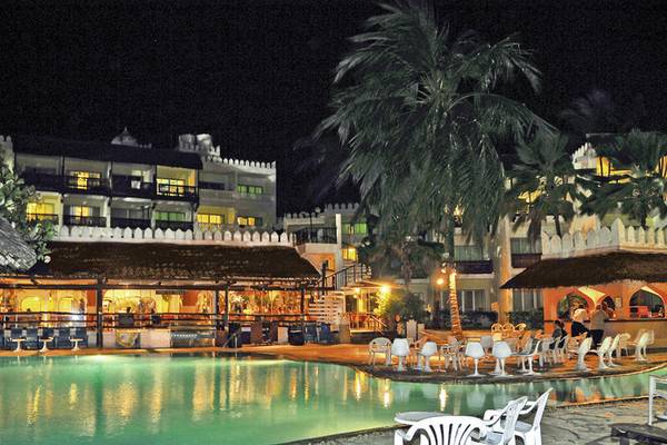 Nachtansicht des Bamburi Beach Hotels mit Swimmingpool und umliegenden Palmen.