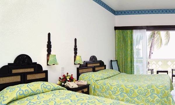 Ein Doppelzimmer im Bamburi Beach Hotel mit zwei Betten, Dekor und Ausblick auf den Garten.