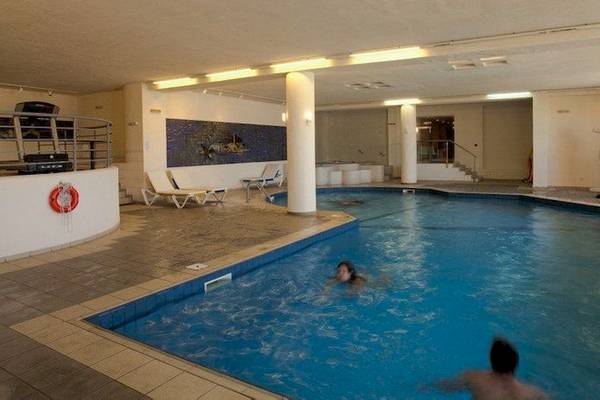 Innenpool des Allsun Hotel Zorbas Village mit zwei Personen, die schwimmen.