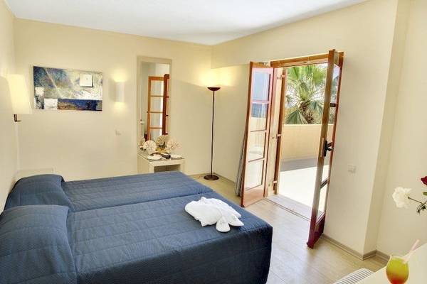 Doppelzimmer im Allsun Hotel Zorbas Village mit zwei Betten, offenem Balkon und Blick auf eine Palme.