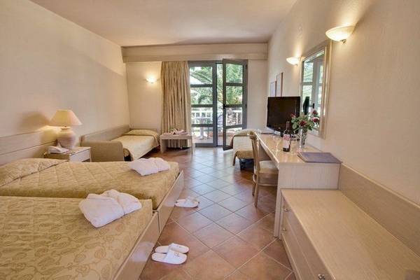 Hotelzimmer im Allsun Hotel Zorbas Village mit drei Betten, Tisch, Fernseher und Balkonzugang.