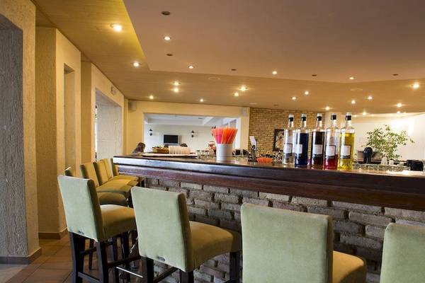 Rezeption im Allsun Hotel Zorbas Village mit Bar und grünen Stühlen.