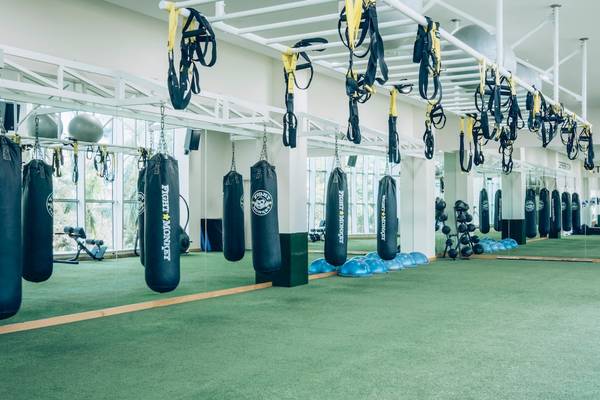 Fitnessstudio mit Boxsäcken und Trainingsgeräten an der Decke hängend.