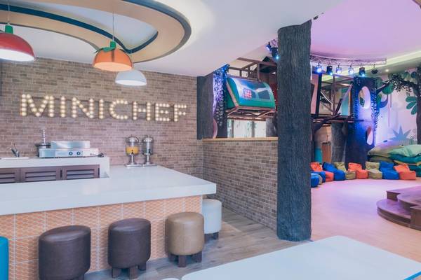 Innenbereich des Iberostar Paraiso del Mar Mini Chef Bereich mit gemauerter Wand, Bar, Stühlen und bunter Bemalung.