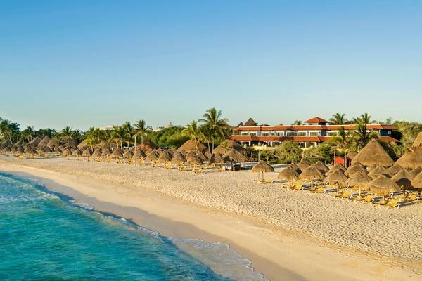 Strand und Hotel Iberostar Paraiso del Mar mit vielen Sonnenschirmen und gelben Liegen.