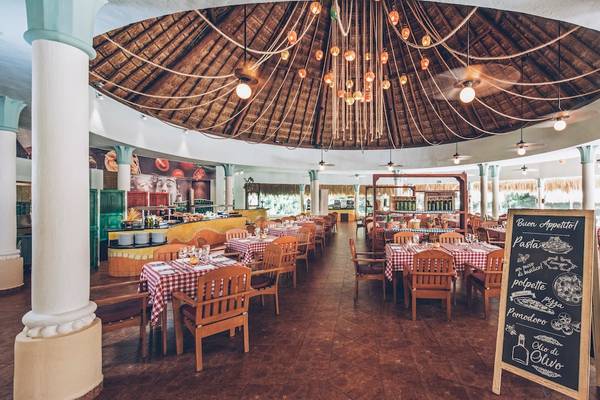 Innenansicht des Restaurants im Iberostar Paraiso del Mar Hotel mit vielen Tischen und Stühlen, einer Tafel und einer Kuppeldecke.