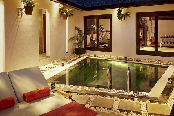Nachtansicht des beleuchteten Schwimmbeckens im Fisherman's Cove Resort mit Loungebereich und Fitnessgeräten im Hintergrund.