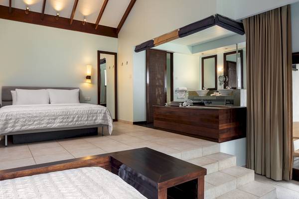 Innenansicht der Suite im Fisherman's Cove Resort mit Bett, Badezimmer und Badewanne.
