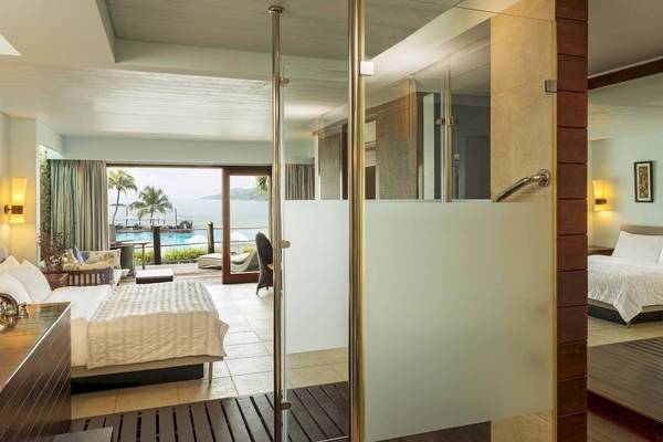 Innenansicht eines Zimmers im Fisherman's Cove Resort mit Blick auf das Meer und eine Terrasse.