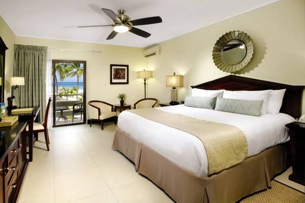Schlafzimmer im Manchebo Beach Resort & Spa mit King-Size-Bett, Klimaanlage, Schreibtisch und Meerblick.