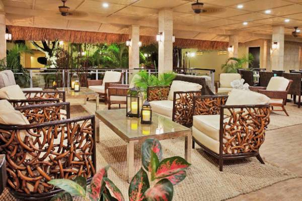 Loungebereich im Manchebo Beach Resort & Spa mit gewebten Möbeln, Pflanzen und Laternen.