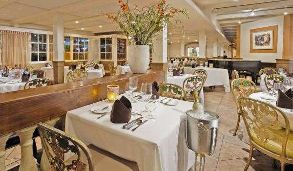 Innenansicht des Restaurants im Manchebo Beach Resort & Spa mit elegant eingerichteten Tischen und Stühlen.