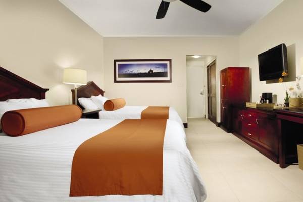 Doppelzimmer im Manchebo Beach Resort & Spa mit zwei Betten, Dekor und Fernseher.