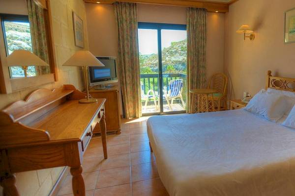 Doppelbettzimmer im Saint Patrick's Hotel Gozo mit Blick auf die Berge und Balkon.