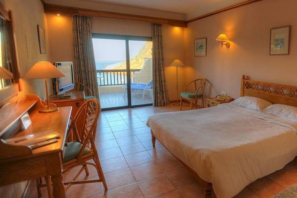 Zimmer im Saint Patrick's Hotel Gozo mit Balkon und Meerblick, inklusive Bett, Schreibtisch und Fernseher.