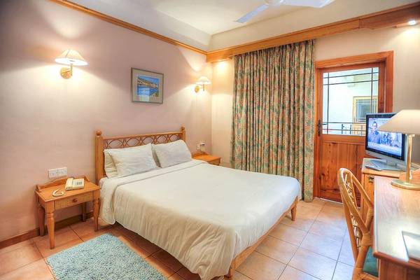 Ein gemütliches Zimmer im Saint Patrick's Hotel Gozo mit einem Bett, Nachttischen und einem Fernseher.